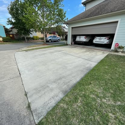 Residential concrete driveway mid-clean showing the dirty side next to a freshly pressure-washed strip.